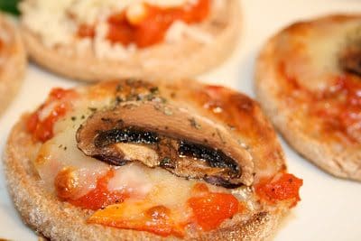 A plate of mushroom and tomato pizzas on a white plate.