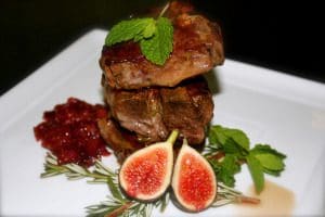 Delicious steak with cranberry sauce served on a white plate.