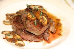 A steak with mushrooms and sauce on a plate, perfect for a recipe.