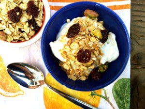 A bowl of homemade granola with yogurt and oranges.