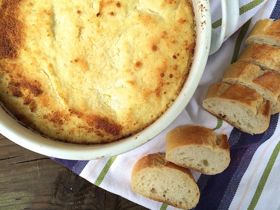 A bowl of food next to a piece of bread.
