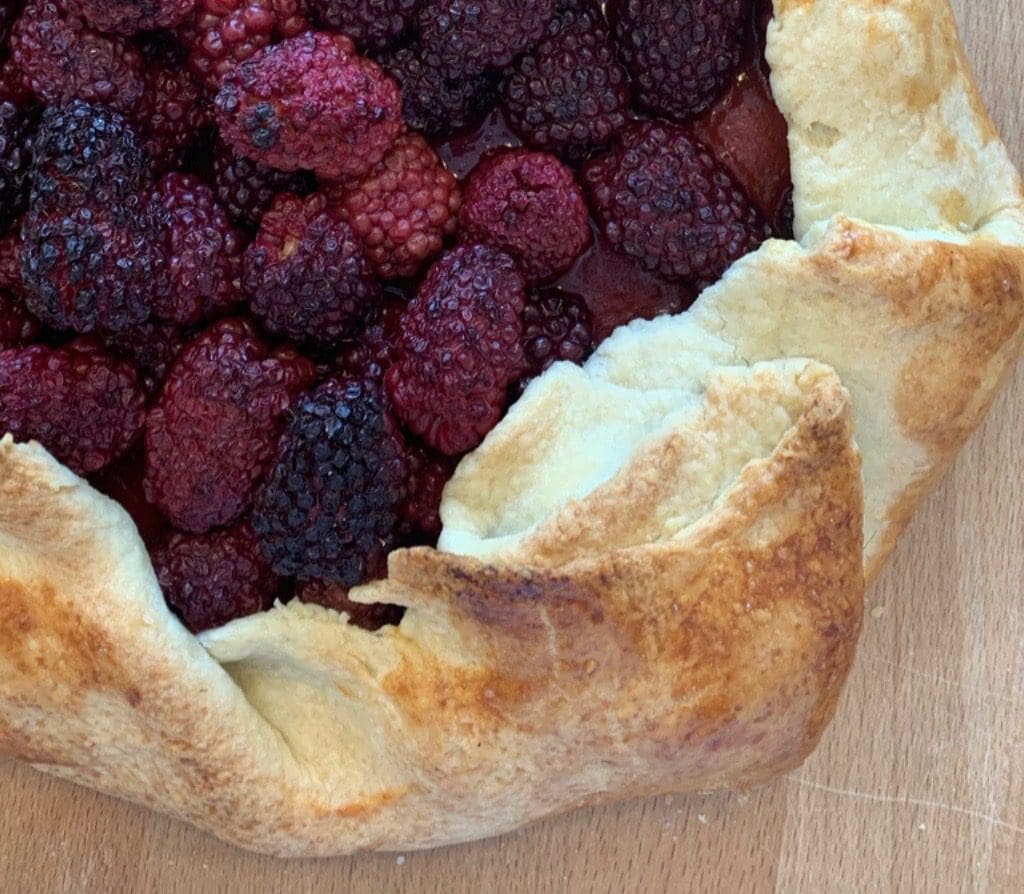 A tart with berries on top of a wooden board.