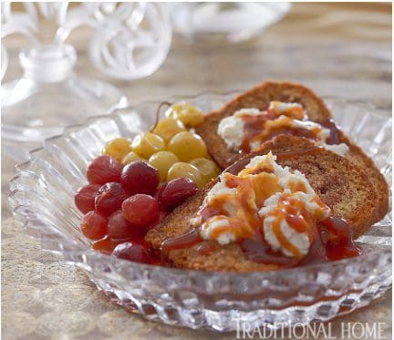 A glass plate with bread and grapes on it.