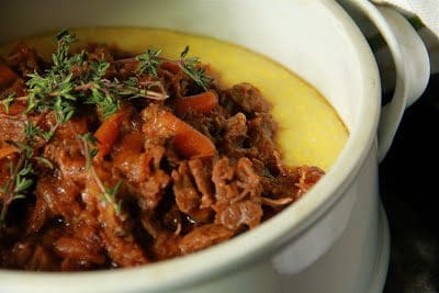 A white bowl with meat and mashed potatoes.