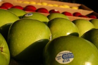 Many green apples are stacked in a crate.