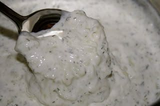 A spoonful of white sauce in a bowl.