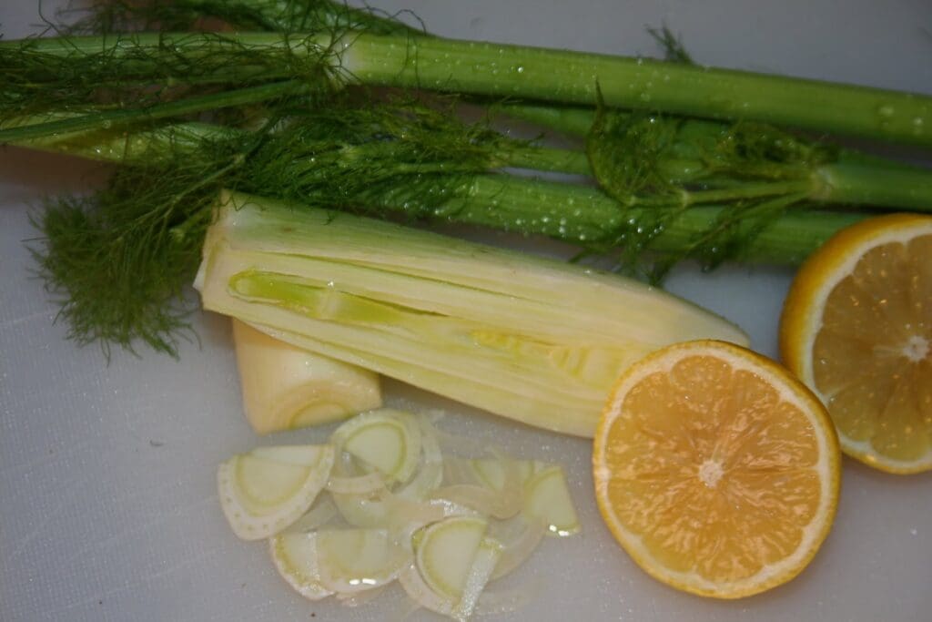 A cutting board with lemons, celery, and fennel.
