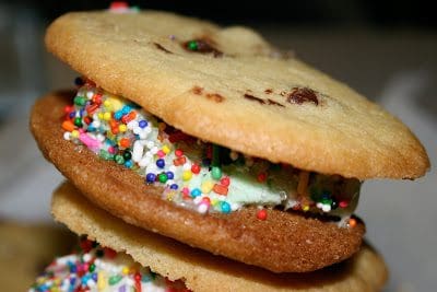 A stack of cookie sandwiches with sprinkles on top.