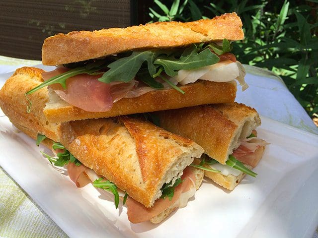 A white plate with four sandwiches on it.