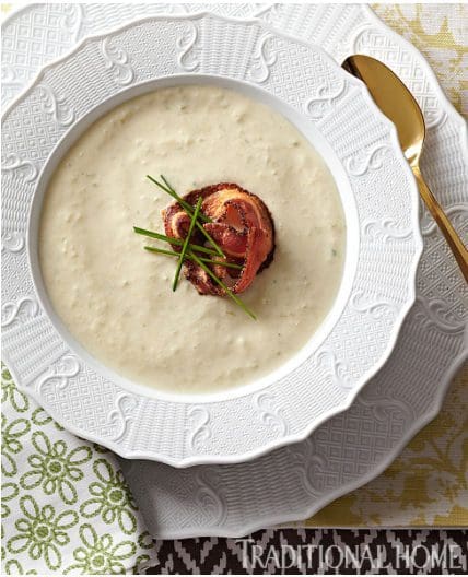 A white bowl of soup with a sprig of thyme.