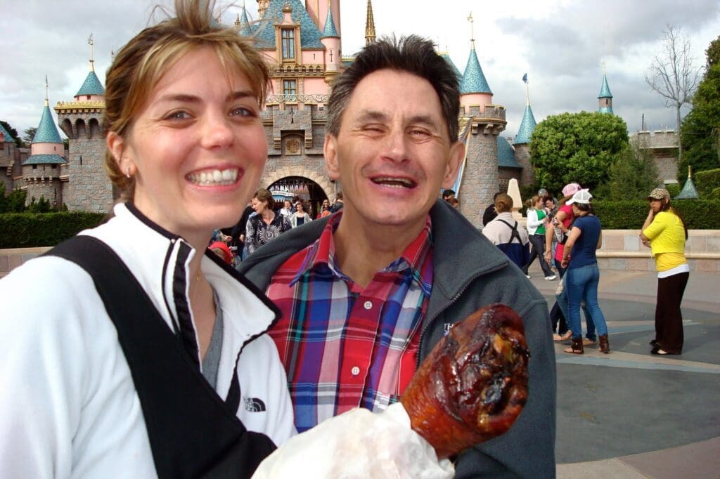 A man and a woman standing in front of disneyland castle.