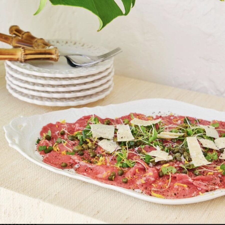 A plate of meat on a table next to a plant.