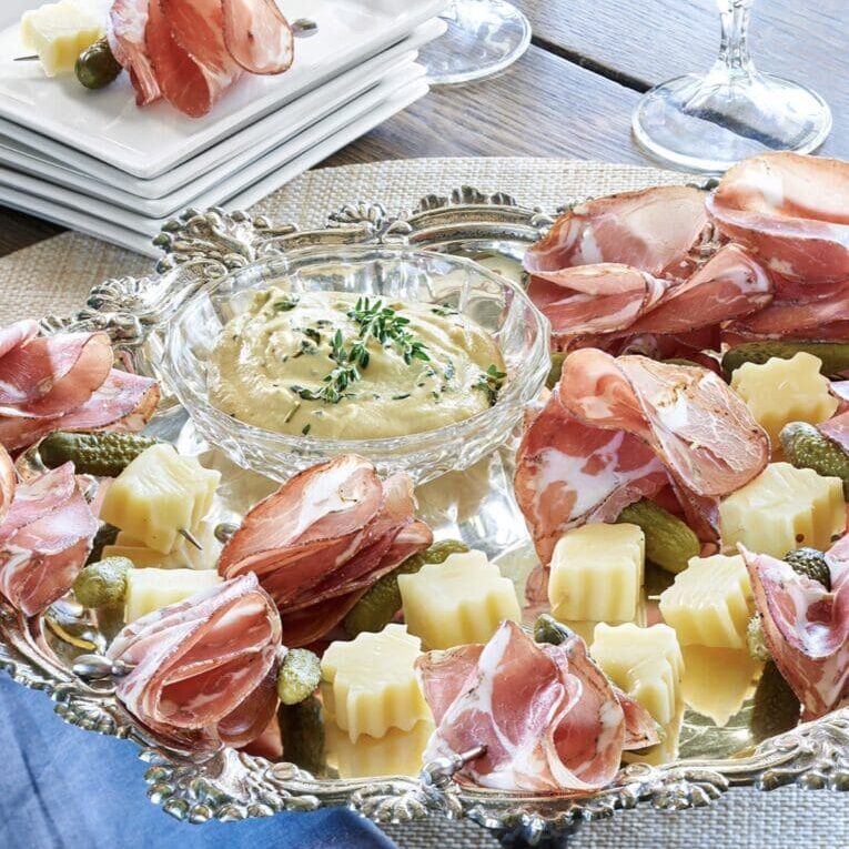 A platter of ham, cheese and pickles on a table.