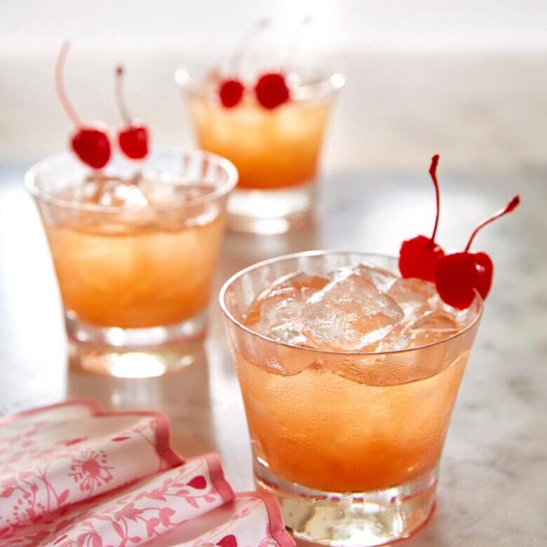 A cocktail with cherries and ice in a glass.