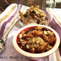 A bowl of cranberry almond granola and a spoon on the table, perfect for breakfast.