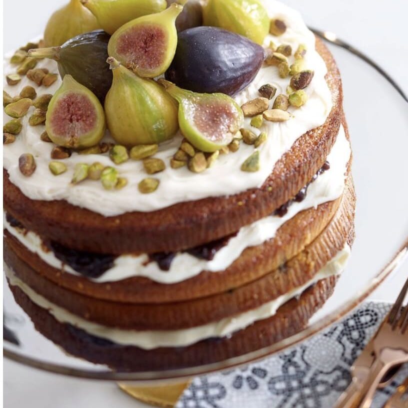 A cake with figs and cream on top.