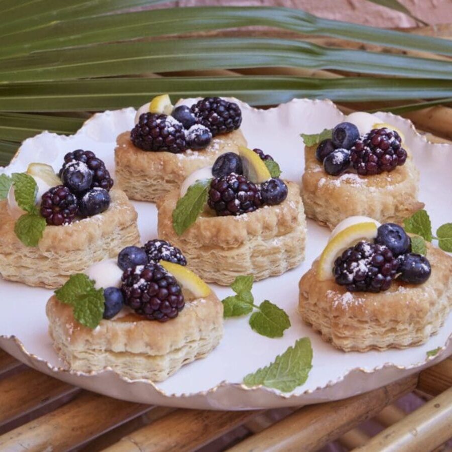 A plate of pastries with blackberries and lemons on it.