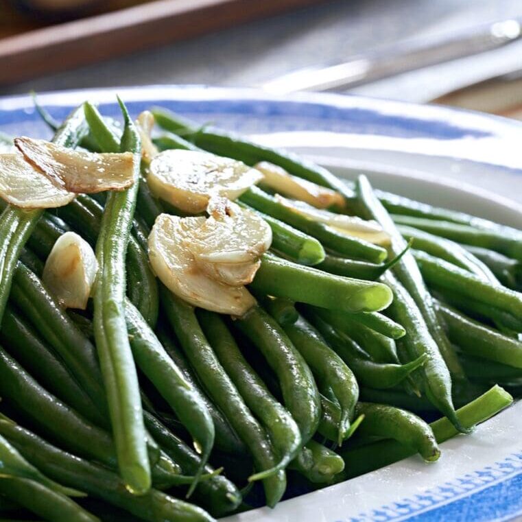 Green beans with garlic on a blue and white plate.