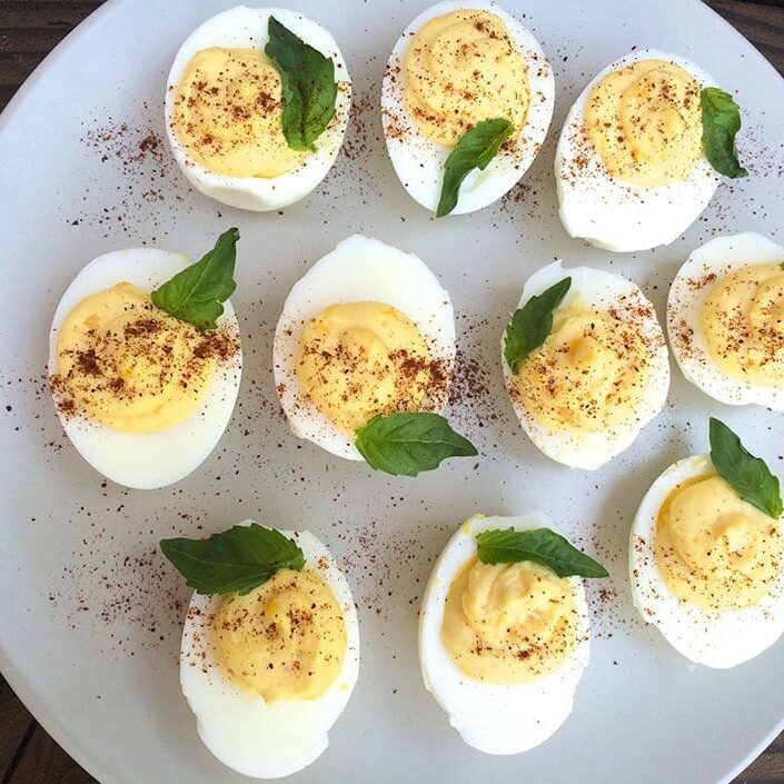 Deviled eggs on a plate with mint leaves.