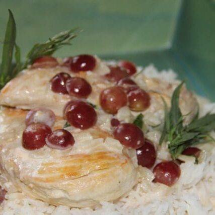 Chicken with grapes and rice in a green bowl.