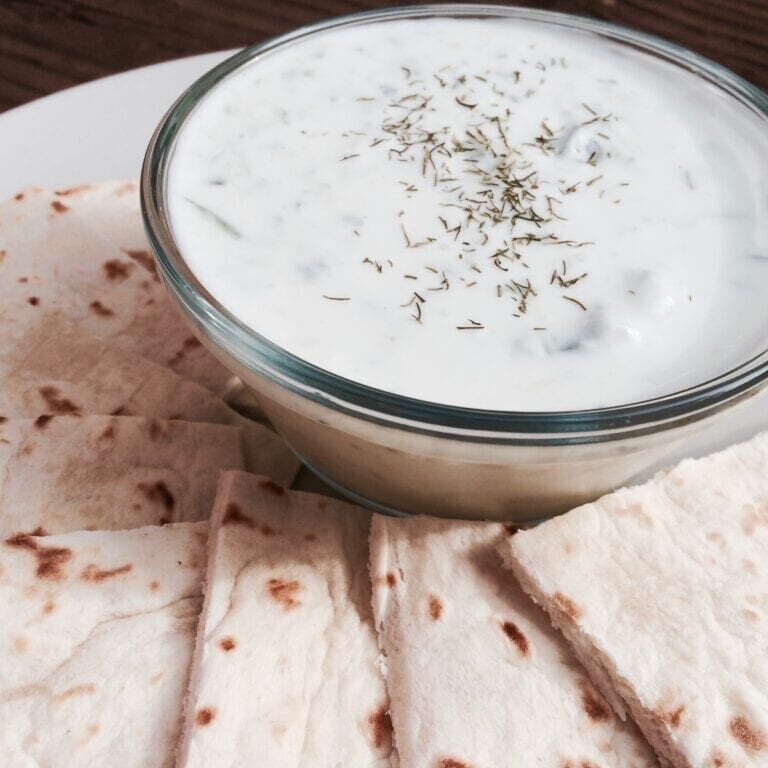 A plate with pita bread and a bowl of dip.