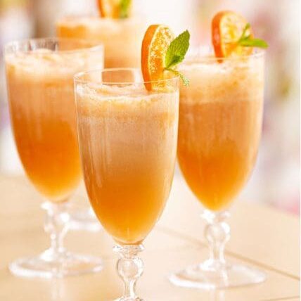 Four glasses filled with orange juice and mint.