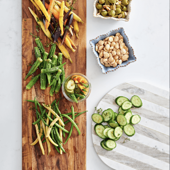 A wooden cutting board with vegetables on it.