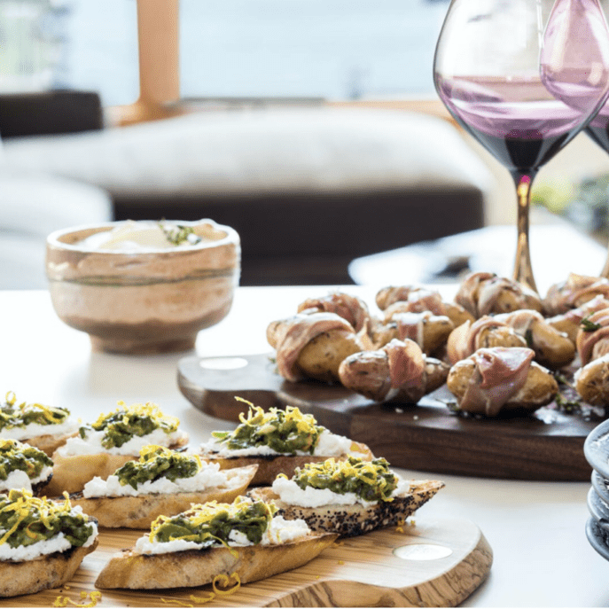 A plate of appetizers on a table next to a glass of wine.