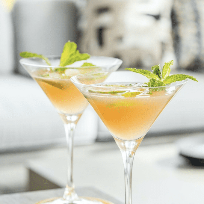 Two martinis on a table with mint leaves.