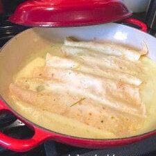 A red skillet on a stove top is ready for cooking.