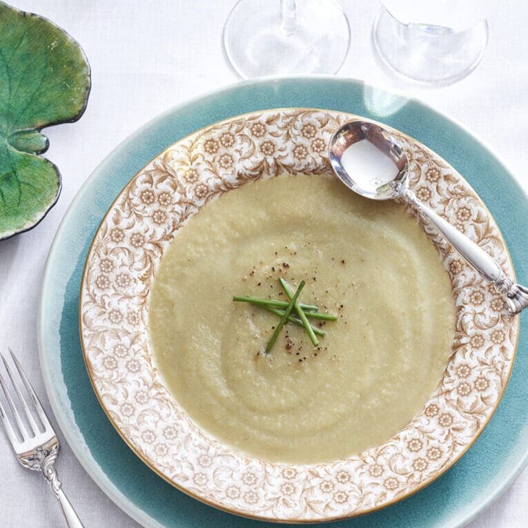 A white plate with a bowl of soup on it.