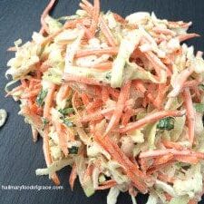 A classic coleslaw recipe made with shredded carrots piled on a cutting board.