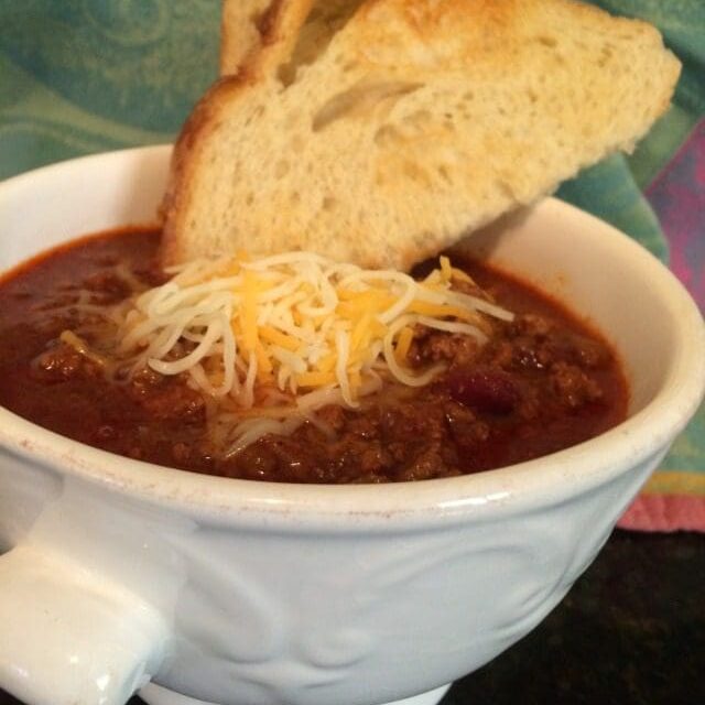 a bowl of Beef chili with a slice of toasted bread