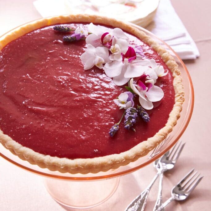 A pie is sitting on a table with flowers on it.